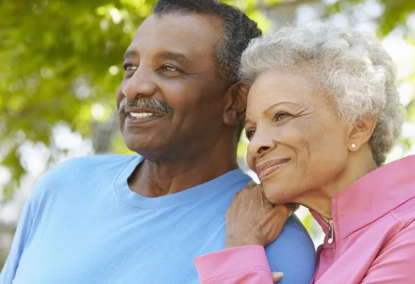 Couple with woman's hand on his shoulder smiling as they look away from camera.
